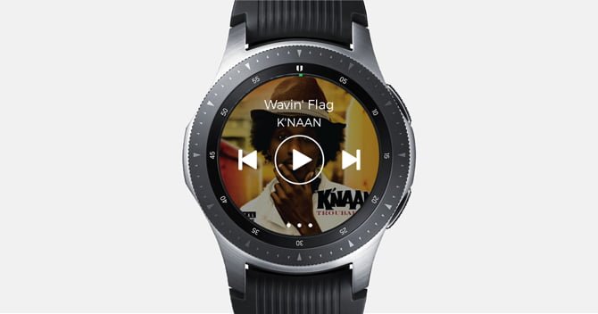 Screenshot of the Galaxy Watch with Spotify app with music controls and album cover in the background.